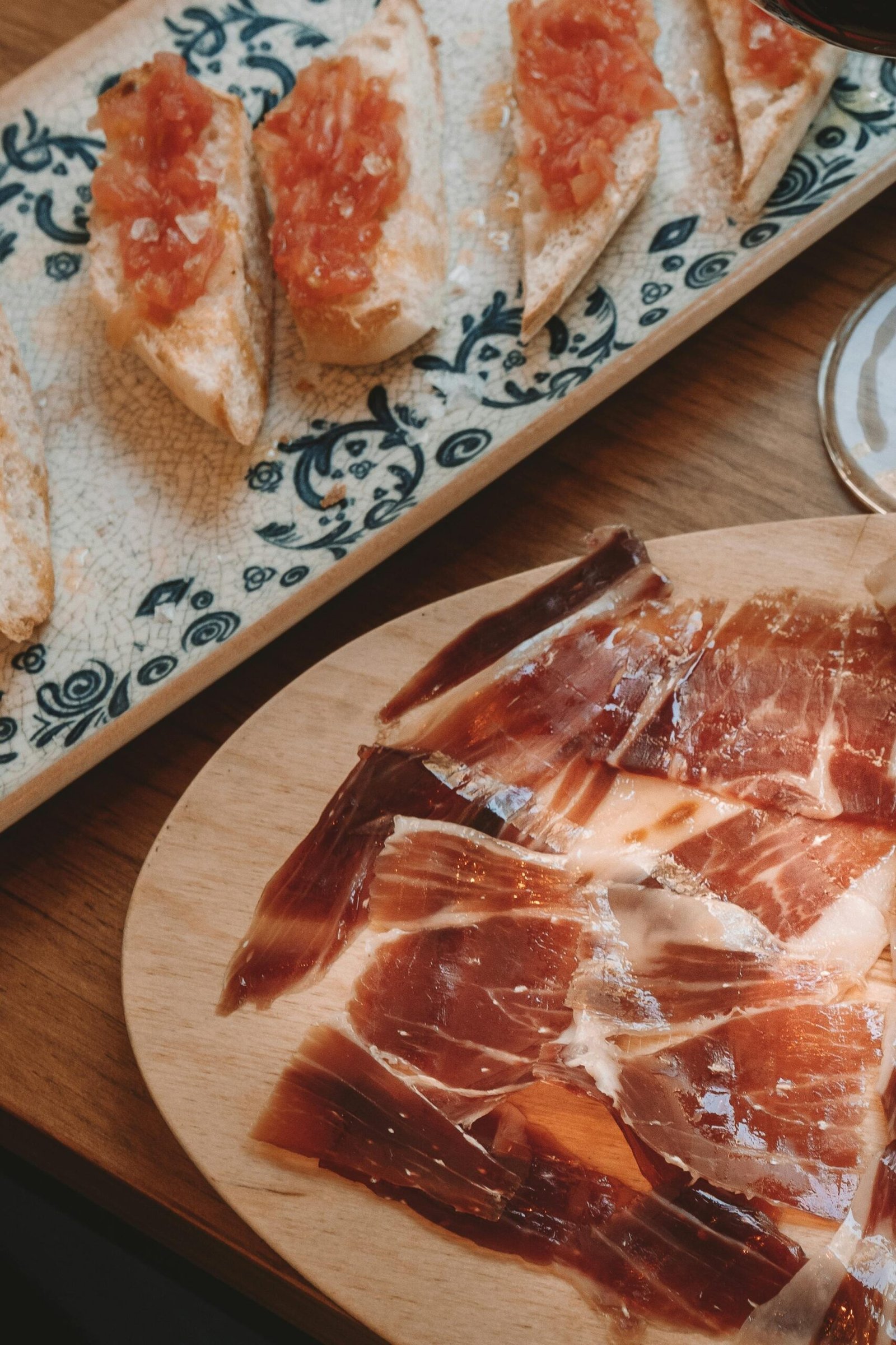 Delicious Spanish tapas featuring Jamón and bread with tomato spread on a ceramic dish.